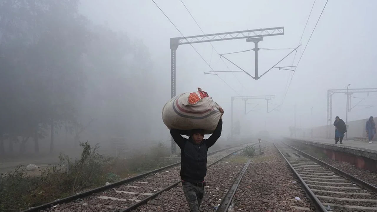 గౌతం బుద్ధ నగర్ దట్టమైన పొగమంచు మధ్య రైలు ట్రాక్‌ను దాటుతున్న ప్రయాణీకులు 