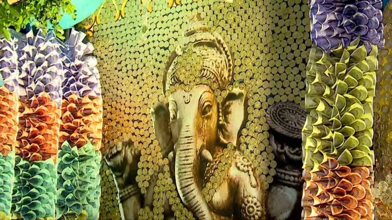 అలాగే 58 లక్షల విలువైన 5, 10, 20 నాణేలు, 10, 20, 50, 100, 200, 500, 2000 రూపాయల నోట్లకు పూలమాలలు వేసి ప్రత్యేకంగా వినాయకుడికి అలంకరించారు. అయితే నోట్ల కట్టలతో, నాణేలతో వినాయకుడికి అలంకరిండచంతో ఈ అలంకారాన్ని వీక్షించే భారీ ఎత్తున భక్తులు తరలిస్తున్నారు. అయియితే భక్తులపై సీసీ కెమెరాల నిఘా, బారికేడ్ వేసి అలంకరణ సొమ్ము ముట్టకుండా ఏర్పాట్లు చేశారు.