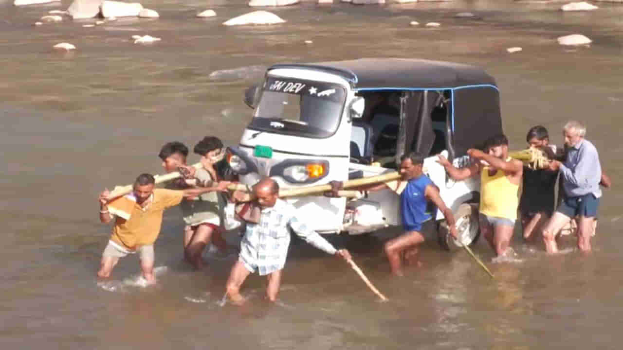 వర్షాలకు కొట్టుకుపోయిన వంతెన.. భుజాల మీద ఆటో వేసుకుని నది దాటుతున్న గ్రామస్తులు