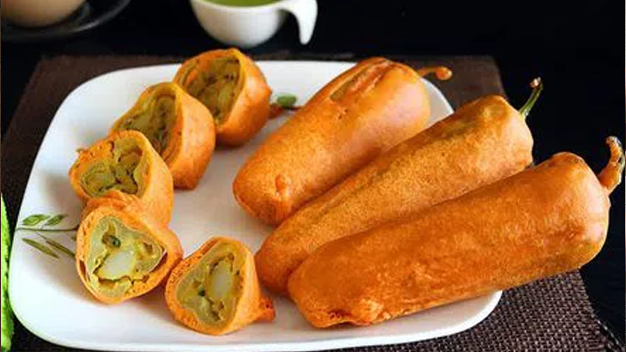  మిరపకాయ బజ్జీలు తయారు చేయడానికి కావాల్సిన పదార్థాలు : కప్పు శనగ పిండి, మిరపకాయలు 8, తినే సోడా చిటికెడు, చింత పండు, రెండు టేబుల్ స్పూన్స్ వాము, ఉప్పు, నూనె, ధనియాల పొడి, ఆనియన్ రెండు, జొన్న పిండి రెండు టీ స్పూన్స్.