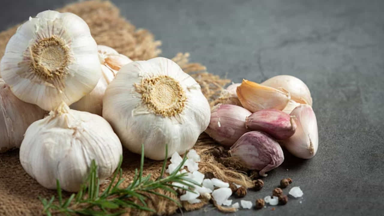 Garlic Tips: వంట చేసేటప్పుడు వెల్లుల్లి పొట్టు తీయడం చాలా మందికి చికాకుగా ఉంటుంది. ముఖ్యంగా ఎక్కువ పరిమాణంలో వెల్లుల్లి అవసరమైనప్పుడు ఇది సమయం తీసుకోవడమే కాకుండా చేతులకు నొప్పి కూడా కలిగిస్తుంది. వెల్లుల్లి పొట్టు తీయడం అంటేనే పెద్ద టాస్క్. కానీ ఒక చిన్న ట్రిక్తో ఈ పని చాలా ఈజీగా చేసేయొచ్చు. దీనికి కొన్ని అవసరమై ఉంటాయి. వాటిని ఉపయోగించి వెల్లుల్లి పొట్టును సులభంగా తీయవచ్చు. అవి ఏంటంటే.. వెల్లుల్లి రెబ్బలకు పట్టించేందుకు కొద్దిగా నూనె, అలాగే మూత ఉన్న డబ్బా (ప్లాస్టిక్ లేదా స్టీల్)