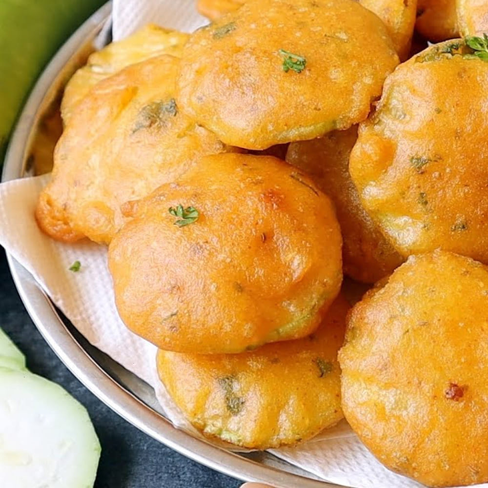 బజ్జీల పిండి కలపడం: ఒక మిక్సింగ్ బౌల్‌లోకి శనగపిండి, బియ్యం పిండి తీసుకోవాలి. బియ్యం పిండి వేయడం వల్ల బజ్జీలు నూనె పీల్చకుండా ఎక్కువసేపు కరకరలాడతాయి. ఇందులో ఉప్పు, కారం, పసుపు, ధనియాల పొడి, అల్లం-వెల్లుల్లి పేస్ట్, సన్నగా తరిగిన కొత్తిమీర, కరివేపాకు వేయాలి. చివరగా వామును అరచేతిలో నలిపి వేయాలి. వాము మంచి సువాసనతో పాటు జీర్ణక్రియకు ఎంతో మేలు చేస్తుంది. ఇప్పుడు కొద్దికొద్దిగా నీళ్లు పోస్తూ ఉండలు లేకుండా బజ్జీల పిండిలా చిక్కగా కలుపుకోవాలి.
