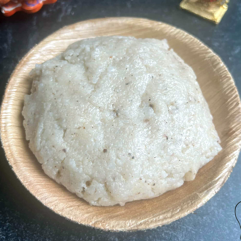 గంట నానిన బియ్యాన్ని కుక్కర్లో వేయాలి. బియ్యానికి నాలుగు రెట్లు (1 లీటర్) నీరు మరియు 20 గ్రాముల ఉప్పు వేసి కలపాలి. కుక్కర్ మూతపెట్టి మీడియం మంటపై 5 విజిల్స్ వచ్చే వరకు అన్నాన్ని చాలా మెత్తగా ఉడికించాలి. ఆవిరి పోయిన తర్వాత మూత తీసి గరిటెతో అన్నాన్ని మెదుపుతూ మెతుకు నలిగేలా కలపాలి. ఇప్పుడు కుక్కర్లో ఉడుకుతున్న ఈ ముద్ద అన్నంలోకి మరో అర లీటర్ మరిగే వేడి నీటిని పోసి గరిటెతో బాగా కలిపి పలుచగా, మృదువైన జారుడు ముద్దలా చేసుకోవాలి.